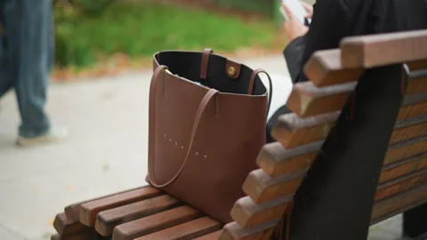 Close up of brown textured handbag resting open with visible contents on wooden Stock Footage 346649043