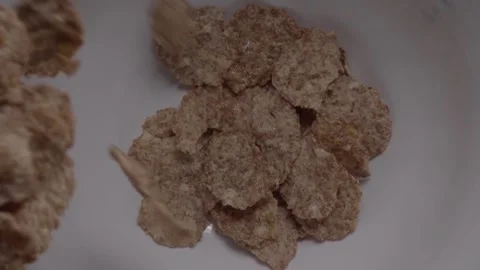 Close Up of Brown Whole Grain Cereal Flakes in Bowl With Flakes Falling Stock Footage 345529903