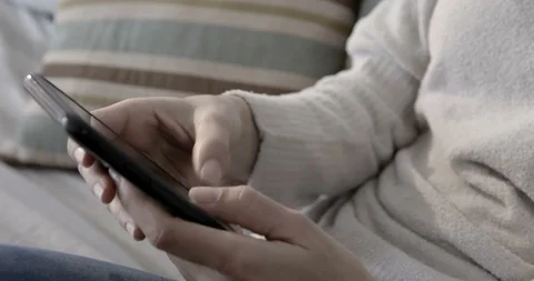 Close up browsing and texting on her phone by the window - 4K Stock Footage 96320374