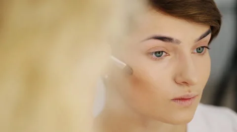 Close-up of brunette female model while applying makeup, contouring cheekbones Stock Footage 64516271