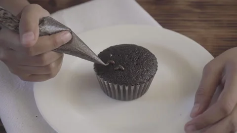 Close up of brunette hand decorating cupcake with plastic handle Stock Footage 142484823