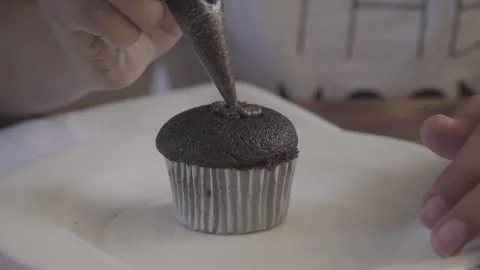 Close up of brunette hand decorating cupcake with plastic handle Stock Footage 142514221