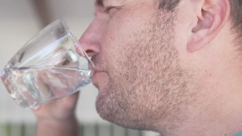 Close-up, brunette man drinking clean drinking water from a glass cup Stock Footage 301254458