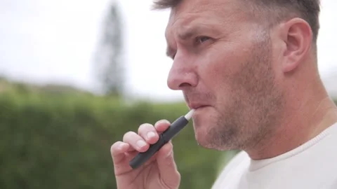Close-up, brunette man smoking e-cigarette on the street Stock Footage 263228563