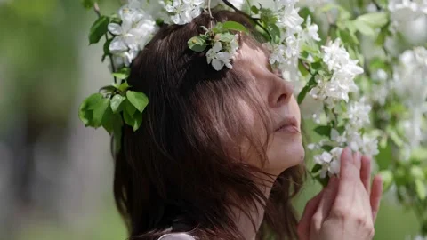 Close-up of a brunette's face and a flowering branch on a sunny day Stock Footage 166164111
