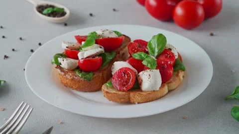 Close-up of Bruschetta with tomatoes, mozzarella and basil leaves Stock Footage 240108115