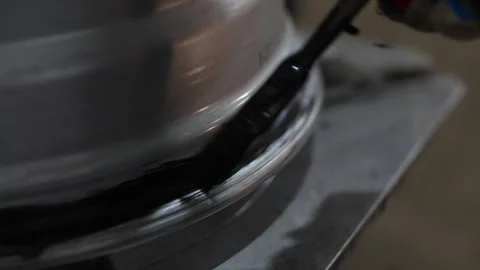 Close-up of brush applying black sealant to rotating car rim Stock Footage 331941577