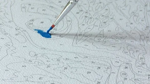 Close-up. a brush with blue paint paints over zones on a picture on numbers Video stock 197648733