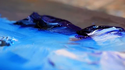 Close-up. The brush takes blue paint on the palette, dilutes the color. 4K Slow Stock Footage