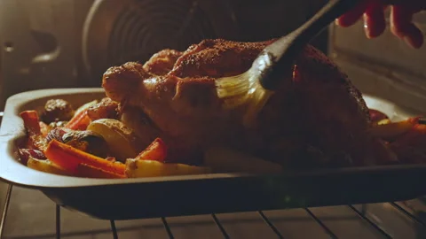 Close-up of brushing and marinating with sauce a whole chicken during grilling. Stock Footage 145117555