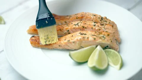 Close-up of brushing cooked salmon with marinade sauce using a basting brush. Video stock 132816553