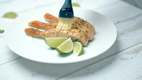 Close-up of brushing cooked salmon with marinade sauce using a basting brush. Stock Footage 132816693
