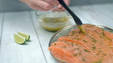 Close-up of brushing raw salmon with marinade sauce using a basting brush. Video stock 132814555