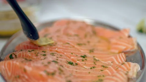 Close-up of brushing raw salmon with marinade sauce using a basting brush. Video stock 132815157