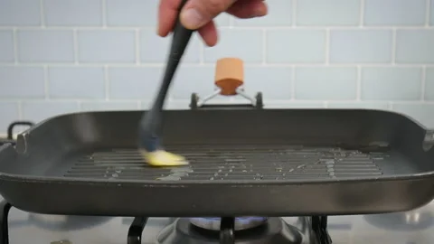 Close-up brushing with a silicone brush a grilling pan with olive oil in 4K. Stock Footage 154345030