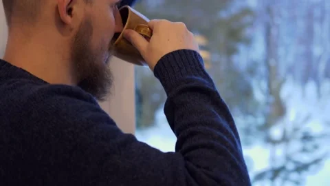 Close-up of a brutal man with a beard stands at the window and looks into the Stock Footage 172248416