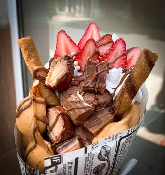 Close up bubble waffle with chocolate bars, ice cream and fresh strawberries Stock Photos