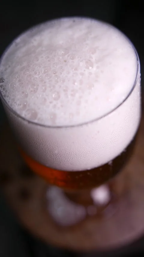 Close-up of bubbles bursting in beer foam. A glass of beer on the table. Stock Footage 331759507