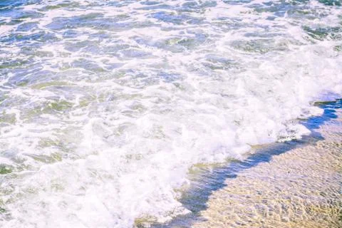 Close up of bubbling sea wave rolling over sand beach Stock Photos
