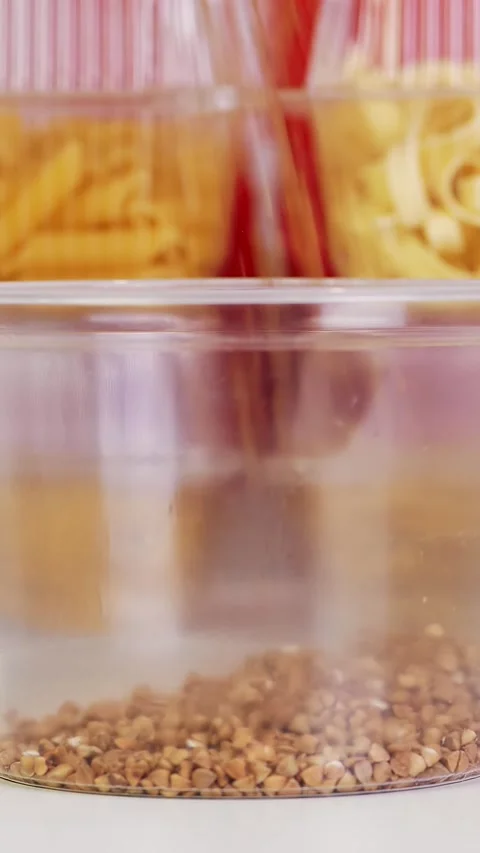 Close-up, buckwheat is poured into plastic packaging. background from the same 스톡 동영상 319943432