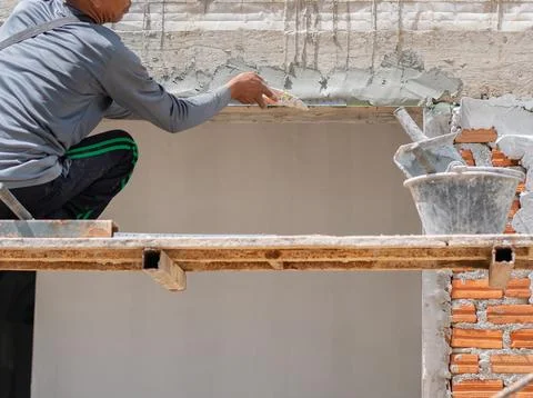 Close-up of a builder applying mortar with a trowel along a line to level a.. Stock Photos