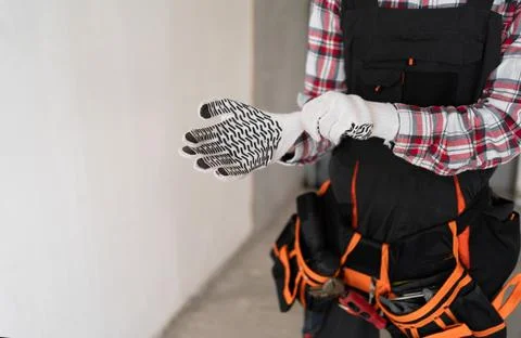 Close up of builder hands putting on work gloves. Construction site and build Stock Photos