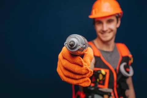 Close up builder is seriously having equipment in arm, isolated over blue Foto stock