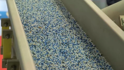 Close-up of bulk material flowing through industrial sorting equipment indoors Video stock 342603932