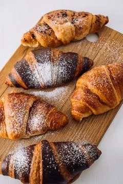 Close up bunch of appetizing brown and chocolate croissants with powdered sugar Stock Photos