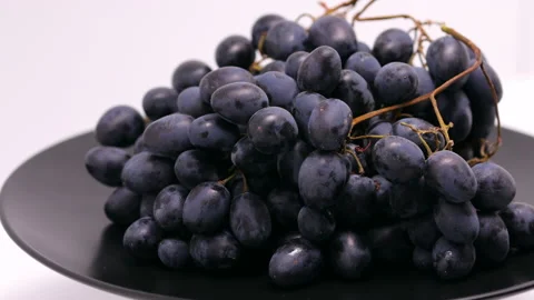 Close-up Of A Bunch Of Black Grapes Rotation On A Black Plate. Black Grapes On A Stock-Footage 149796555
