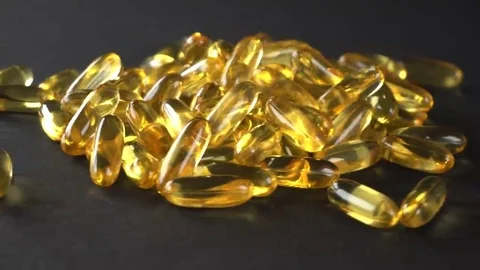 Close up of a bunch of capsule pills rotating on a black background. Seamless Stock Footage 69233440