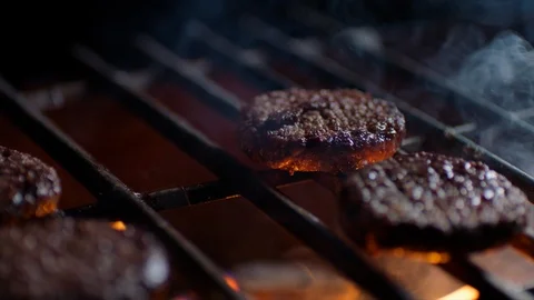 Close up of burger cutlets on grill with fire flames, slow motion Stock Footage 92689064