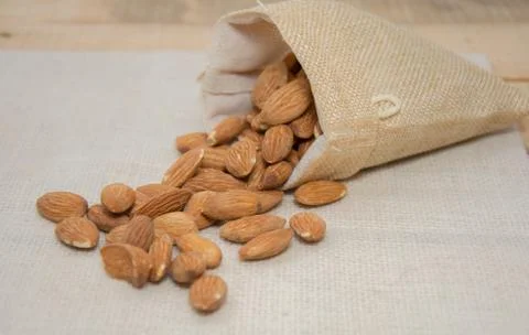 Close up of Burlap sack with almonds spilling out Stock Photos