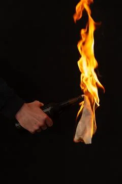 Close-up of burning bottle in hand on black background, Foto stock