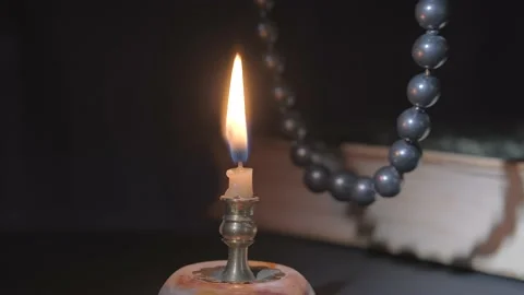 Close-up of a burning candle and going through a rosary Stockbeeldmateriaal 167253729
