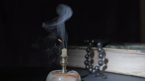 Close-up of a burning candle and prayer beads on an old book out of focus Stock Footage 167253741