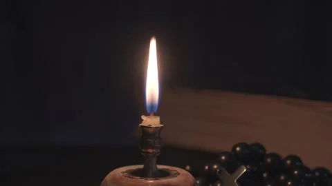 Close-up of a burning candle on the background of a rosary and an old book Video stock 167253917