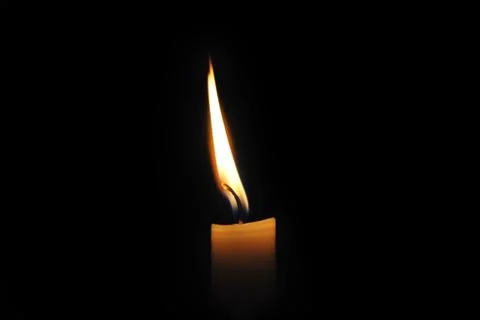 Close-up of a burning candle on a black background. Stock Photos