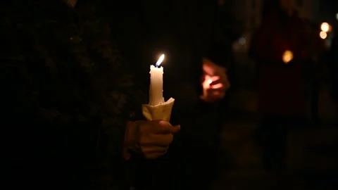 A close-up of a burning candle held in a hand at night. Stock Footage 270253997