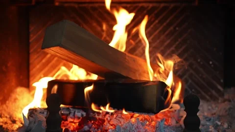 Close-up of a burning log in a fireplace with orange flames, embers, and ash Stock Footage 327689872