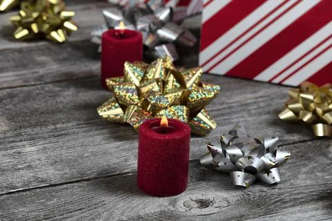 Close up of a burning red candle with gift boxes and silver or gold bow Stock Photos