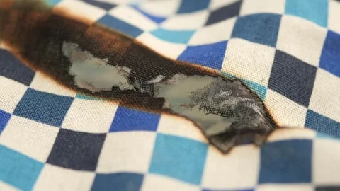 Close up on burnt checkered fabric with wavy texture and melting fibers. Stock Footage 332105601