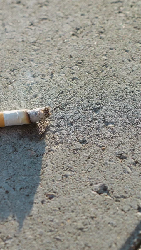 Close up of burnt cigarette resting steadily on rough concrete surface with soft Stock Footage 347694001