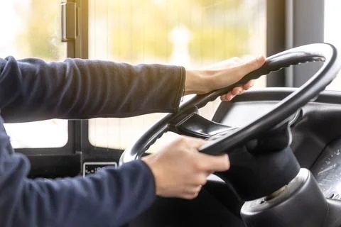 Close up of bus driver hands on the steering wheel during driving the bus 库存照片
