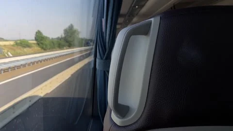 Close-up bus seatback handle with highway view through window during daytime Vidéo 344587657