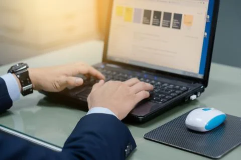 Close up of business person's hands using laptop on table in the office. Clos Stock Photos
