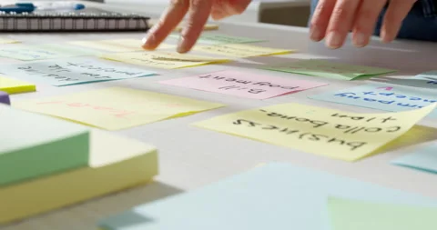 Close-up of a business woman's hands using a startup project work note post.  Video stock 151099252