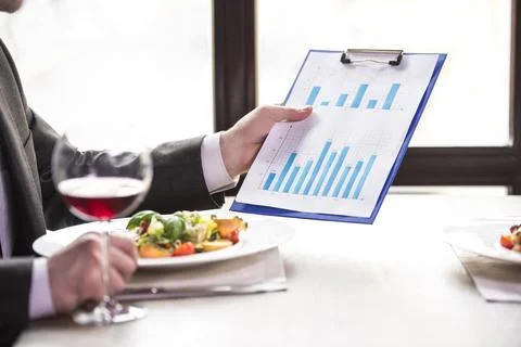 Close-up. Businessman analyzing graphs during a business lunch. Stock Photos
