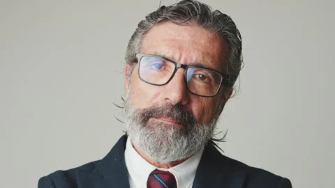 Close-up of businessman in glasses looking at the camera, isolated on gray Stock Footage 252502854