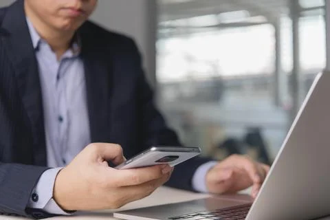 Close up businessman hand using smartphone and laptop computer for work. Co.. Stock Photos